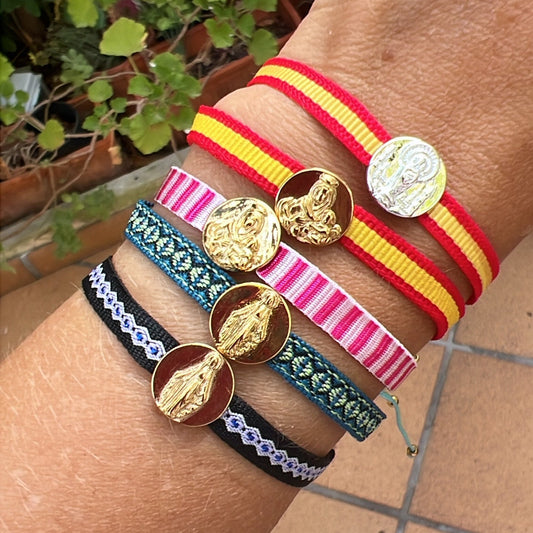 pulsera de cordón ajustable con medalla de la virgen del rocío, covadonga, milagrosa, del carmen y la milagrosa. es de acero hipoalergénico bañado en oro o plata. la cinta es de la bandera de españa, rosa, azul o negra. Es resistente al agua y apta para niños y hombre.