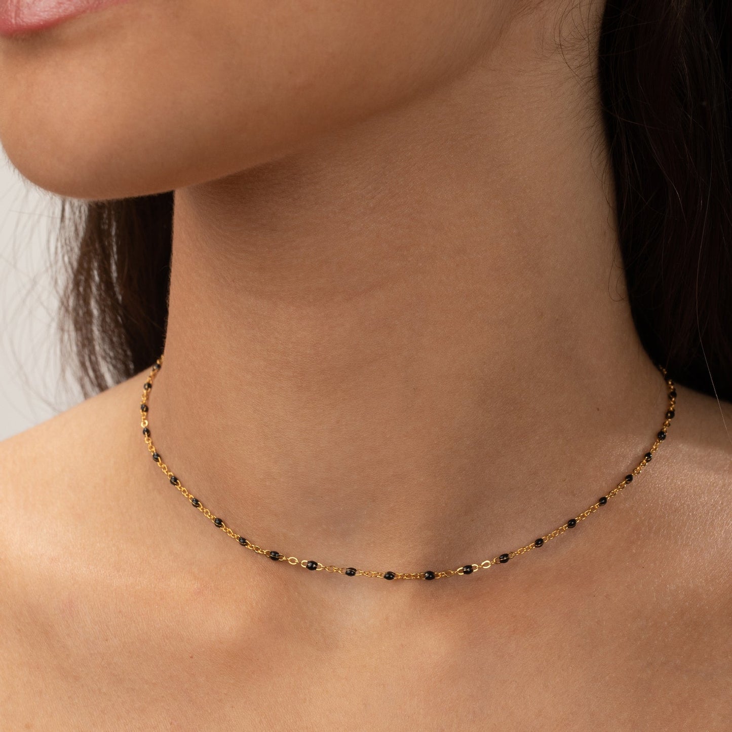 gargantilla dorada waterproof o resistente al agua confeccionada en acero con baño de oro de 3 micras. Tiene bolitas de enamel negras y el cierre es ajustable. collar hipoalergénico e inoxidable. gold plated stainless steel black bead necklace.