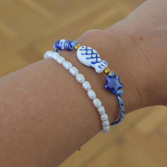 pulsera DE VERANO waterproof o resistente al agua confeccionada con cordón de algodón, abalorios de cerámica y acero dorado. Cierre ajustable, colgante de estrella de mar y pez azul y blanco. Ideal para regalar a mujeres, niñas y adolescentes en vacaciones.