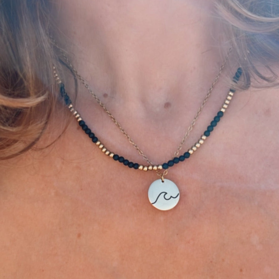 gargantilla de acero hipoalergenico y resistente al agua para bañarse en la piscina o en el mar. Tienes franjas de color negro y dorado. Perfecta para verano, otoño, invierno y primavera