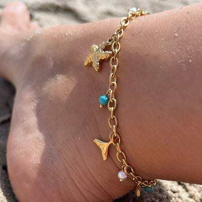 tobillera para verano resistente al agua en colores dorado,  azul turquesa y coral. tiene abalorios de concha, ESTRELLA DE MAR Y cola de ballena. Es de acero hipoalergénico
