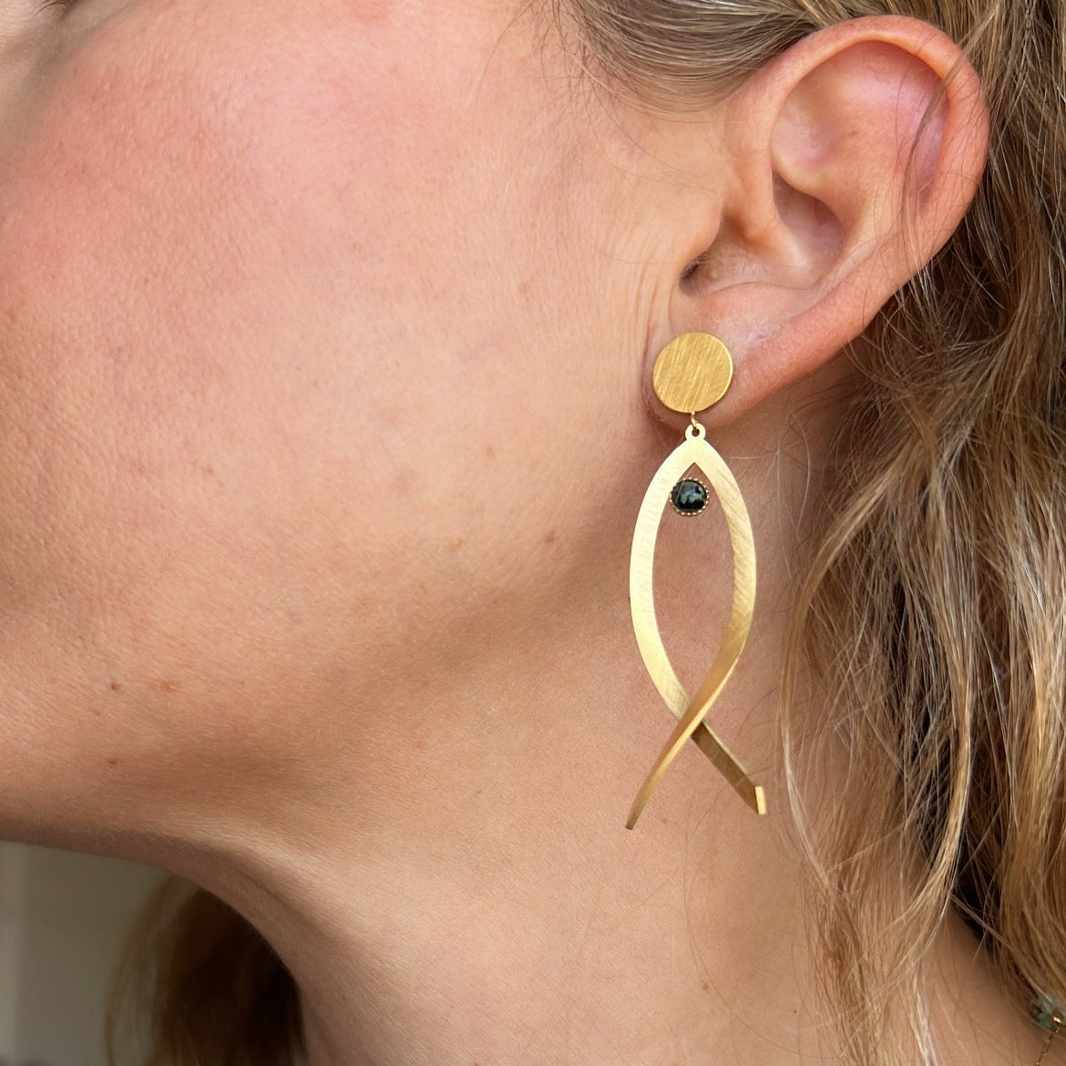 pendientes huecos ligeros con forma de pez y el ojo es de piedra natural africana verde. Son de acero hipoalergénico y resistente al agua. Son dorados y perfectos para looks casual de diario y para llevar en la piscina o en el mar. 