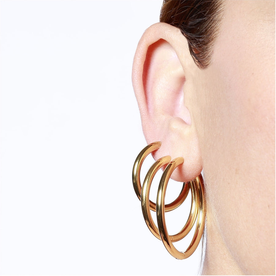 Aros básicos grandes de piercing con cierre fácil resistentes al agua. Son hipoalergénicos y están confeccionados en acero inoxidable con baño de oro 18 kilates. Gold plated stainless steel waterproof hoop earrings for piercing.