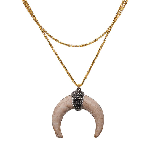 collar largo con colgante de cuerno media luna en piel color marfil. la cadena es de acero hipoalergénico y resistente al agua