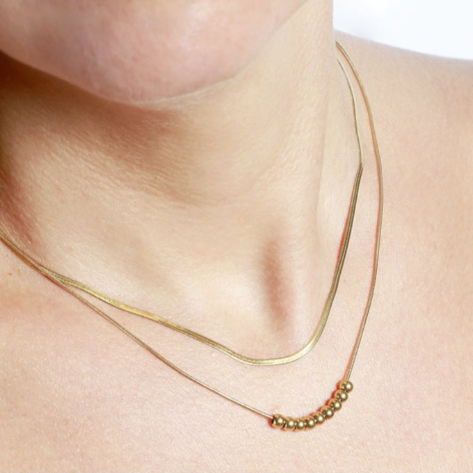 Collar boho de dos cadenas juntas, una de bolitas y otra de escama herringbone. Es de acero hipoalergénicos resistente al agua. Son 2 collares en 1.