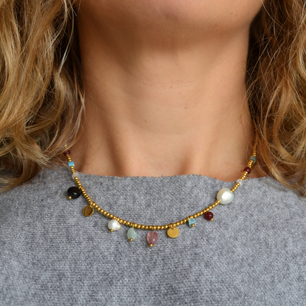 COLLAR waterproof o resistente al agua confeccionada en acero con baño de oro 18 kilates. Tiene abalorios de colores imitando piedra natural y perla cultivada. 