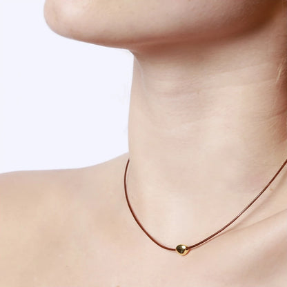 collar de hilo o cordón en color marrñon con bolita plateada o dorada. Gold plated sterling silver bead brown thread necklace.