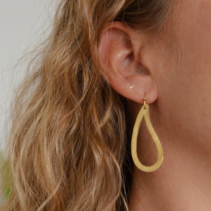 pendientes huecos ligeros con forma de ameba o estampado paisley. Son de acero hipoalergénico y resistente al agua. Son dorados y perfectos para looks casual de diario y para llevar en la piscina o en el mar. 