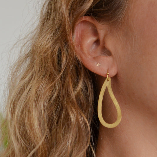 pendientes huecos ligeros con forma de ameba o estampado paisley. Son de acero hipoalergénico y resistente al agua. Son dorados y perfectos para looks casual de diario y para llevar en la piscina o en el mar. 