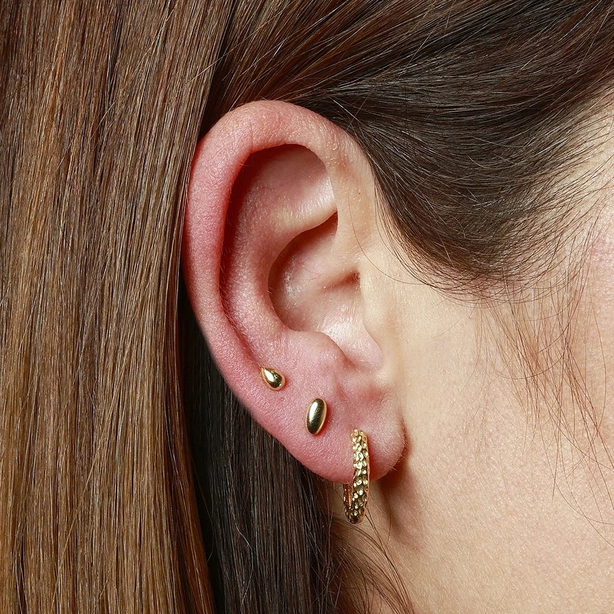 pendientes de piercing hipoalergénicos para cartílago o helix. Son de plata de ley con baño de oro 18 kilates. Tienen forma de óvalo o gota y cierre plano por detrás.