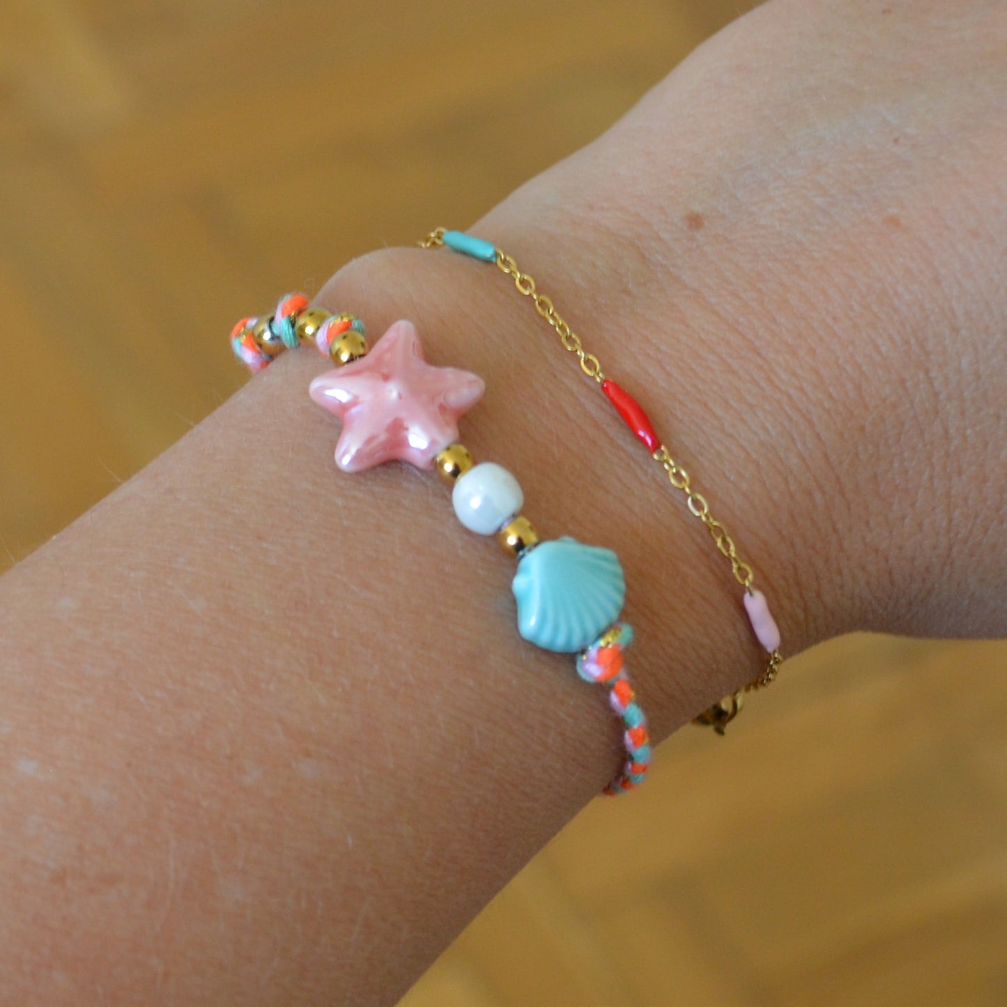 pulsera DE VERANO waterproof o resistente al agua confeccionada con cordón rosa con abalorios de cerámica y acero dorado.  Cierre ajustable, colgante de estrella de mar y concha en color rosa y azul turquesa. Ideal para regalar a mujeres, niñas y adolescentes en vacaciones.