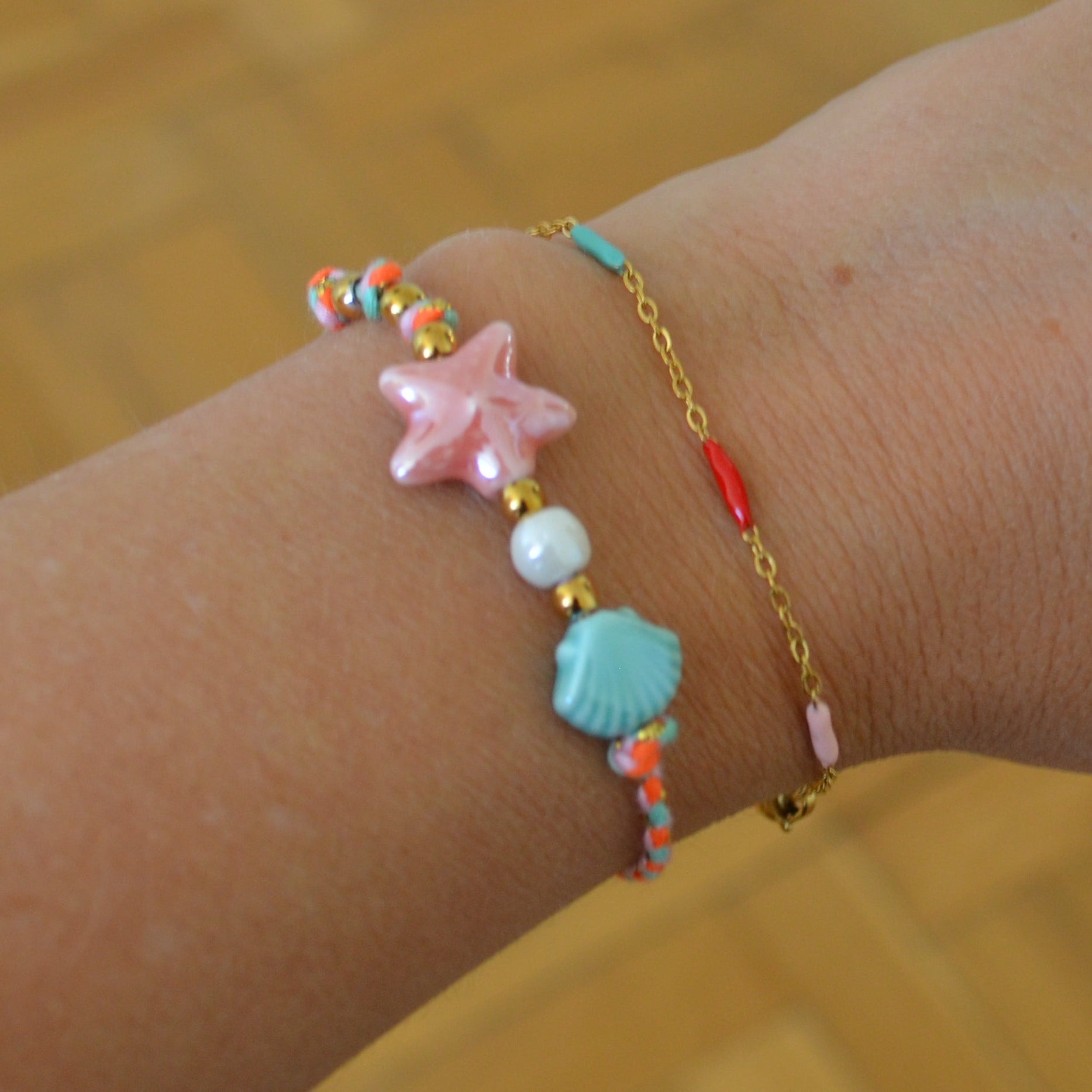 pulsera DE VERANO waterproof o resistente al agua confeccionada con cordón rosa con abalorios de cerámica y acero dorado.  Cierre ajustable, colgante de estrella de mar y concha en color rosa y azul turquesa. Ideal para regalar a mujeres, niñas y adolescentes en vacaciones.