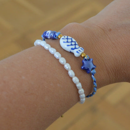 pulsera DE VERANO waterproof o resistente al agua confeccionada con cordón de algodón, abalorios de cerámica y acero dorado.  Cierre ajustable, colgante de estrella de mar y pez azul y blanco. Ideal para regalar a mujeres, niñas y adolescentes en vacaciones.