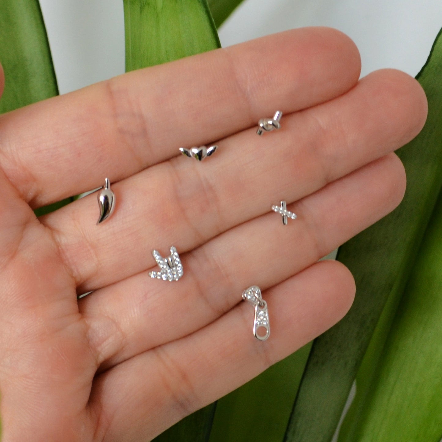 pendientes pequeños para piercing de plata de ley con baño de oro 18 kilates. Tienen forma de nudo, guindilla, cremallera, equis, corazón con alas y mano rockera