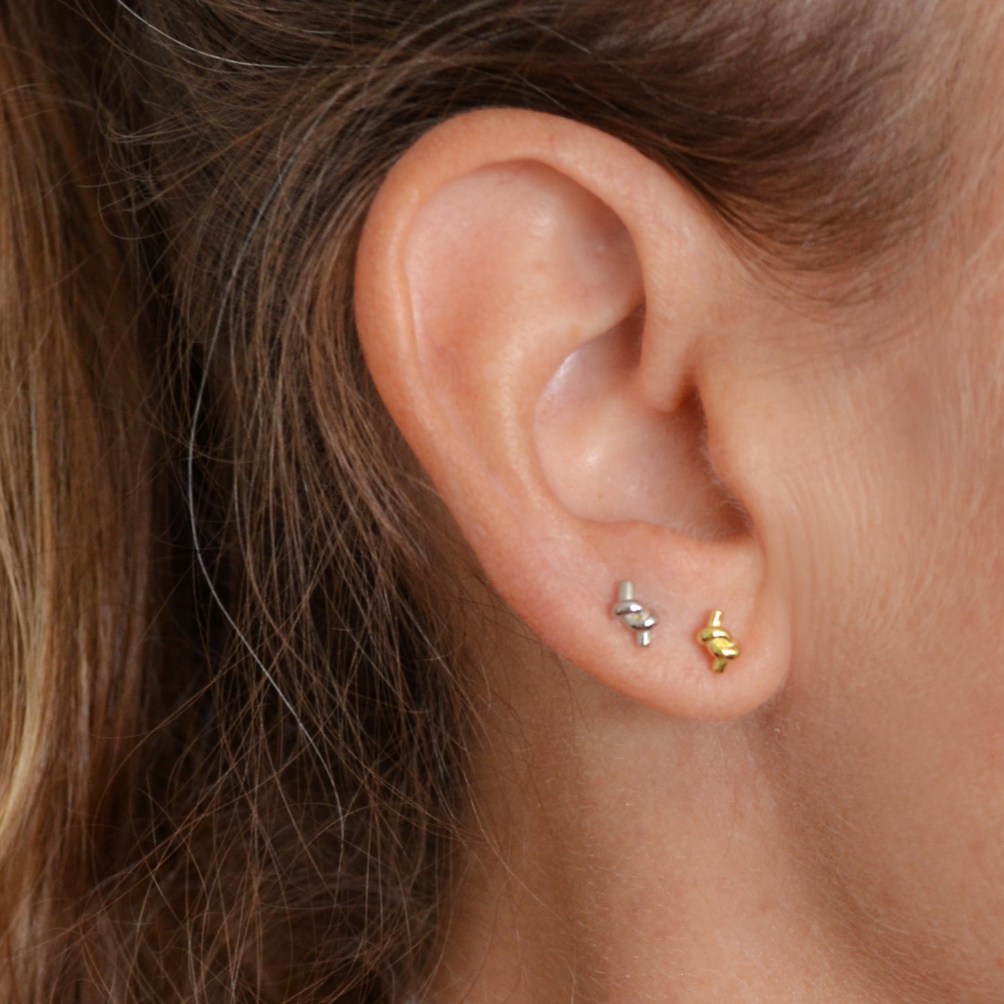 pendientes pequeños de piercing en forma de nudo. Son de plata de ley con baño de oro 18 kilates.