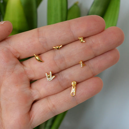 pendientes pequeños para piercing de plata de ley con baño de oro 18 kilates. Tienen forma de nudo, guindilla, cremallera, equis, corazón con alas y mano rockera