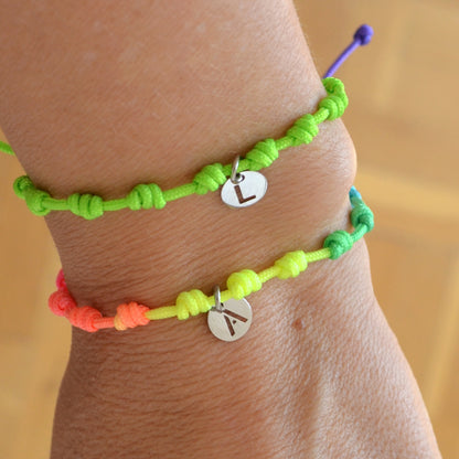 Pulsera para verano fluor con nudos de colores. Está confeccionada en cordón encerado con nudos. Se puede personalizar con un colgante de letra con las iniciales de los hijos o los nietos. El cierre es ajustable. Es un regalo perfecto para niñas o para el dia de la madre. 