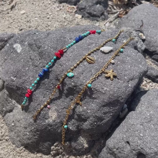 tobillera para verano resistente al agua en colores dorado,  azul turquesa y coral. tiene abalorios de concha, ESTRELLA DE MAR Y cola de ballena. Es de acero hipoalergénico
