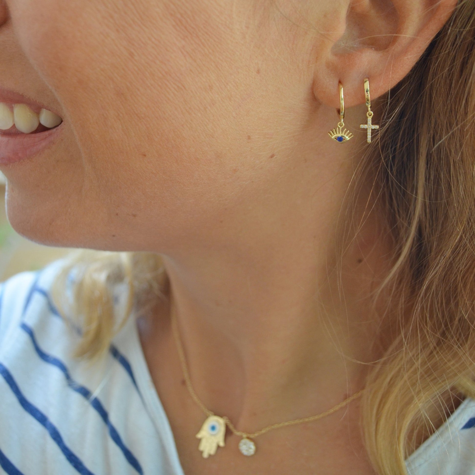 aros pequeños con colgante o charm en forma de cruz con circonitas y confeccionados en plata de ley y baño de oro 18 kilates